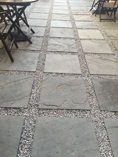 an outdoor patio with tables and chairs, graveled in to the walkways that lead up to the dining area