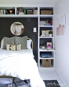 a white bed sitting in a bedroom next to a book shelf