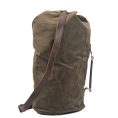 the waxed canvas duffel bag with brown leather straps is shown against a white background