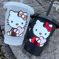 two hello kitty tumblers sitting on top of a wooden table next to each other