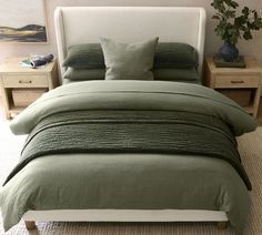 a bed with two nightstands and a green comforter on top of the bed