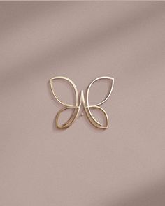 a gold butterfly brooch pin sitting on top of a pink background with the word love written in it