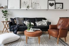 a living room with black leather couches and white wall art on the shelves above