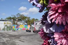 colorful flowers are hanging from the side of a truck in front of a graffiti covered building