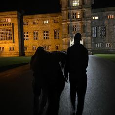 a man is walking with his horse down the street at night in front of an old building