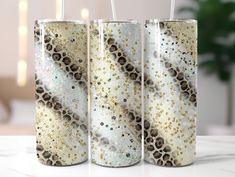 three canisters with gold and white designs on them sitting on a marble surface