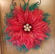 a red poinsettia with green leaves hanging on a door