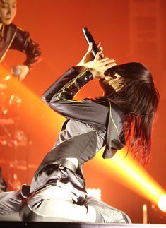 a woman holding a cell phone while standing on top of a stage