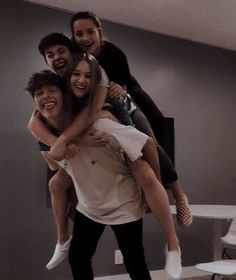 a group of people standing around each other in a living room with grey walls and white furniture