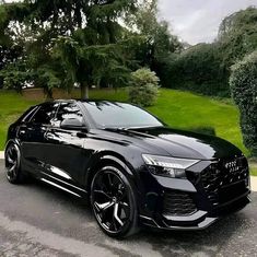 a black audi suv parked on the side of a road in front of some trees