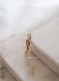 an image of a wedding ring with the words bobbie written below it on top of a marble surface