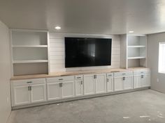 an empty room with white cabinets and a flat screen tv mounted on the back wall