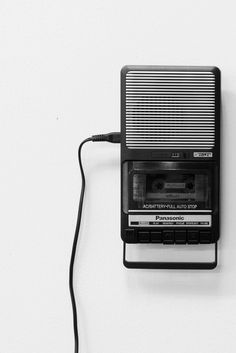 an old fashioned radio is plugged into a charger on a white wall with a black cord