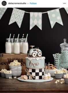 a birthday cake with cars on it sitting in front of other desserts and snacks