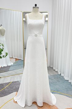 a white wedding dress is on display in front of a mirror and mannequin