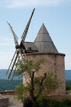 an old building with a tree in front of it and a windmill on top of it