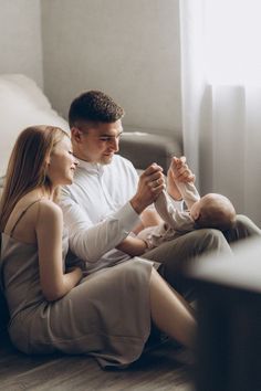 a man and woman sitting on the floor holding a baby