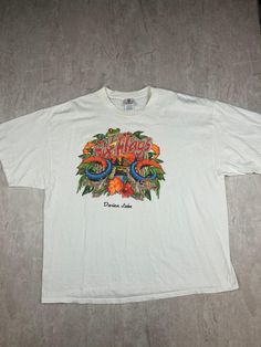 a white t - shirt with an image of a snake and flowers on the front