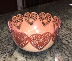 a pink bowl with hearts on it sitting on a counter