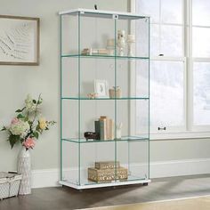 a glass shelf with flowers and books on it