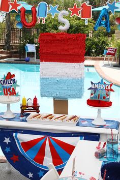 an american flag cake on a table next to a pool with flags and bunting