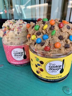 two ice creams with m & m cookies in them sitting on a blue table