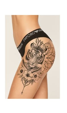 a woman's thigh with a tiger tattoo on the side and flowers around it