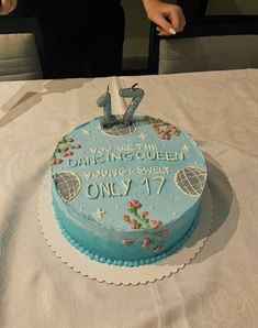 a blue cake with the number twenty seven on it sitting on top of a table