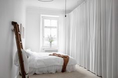 a bedroom with white walls and curtains on the windowsill