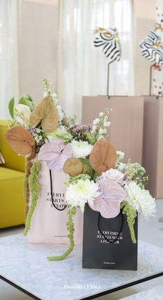 two shopping bags with flowers in them sitting on a table