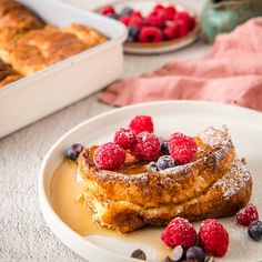 french toast on a plate with raspberries and blueberries next to the bread