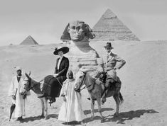 three men and two women riding camels in front of the pyramids