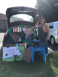 a woman and child standing next to an open car trunk with decorations on the hood