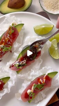 someone is cutting up sushi on a plate with avocado and limes