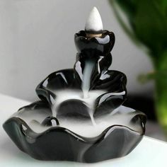 a black and white vase sitting on top of a table next to a potted plant