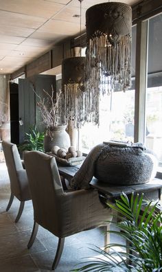 the dining room table is surrounded by chairs and potted plants in front of large windows