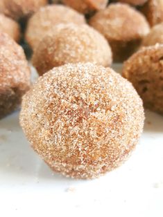 some sugared doughnuts are sitting on a white surface next to other pastries