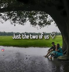 two people sitting under a tree in the water