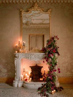 a fireplace with candles and flowers on the mantle