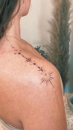 the back of a woman's shoulder with an arrow and stars tattoo on it