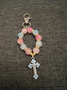 a bracelet with a cross on it and some beads hanging from the end of it