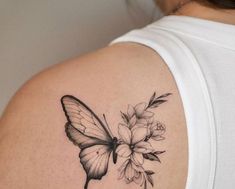 a woman's shoulder with a butterfly and flowers tattoo on her left upper arm