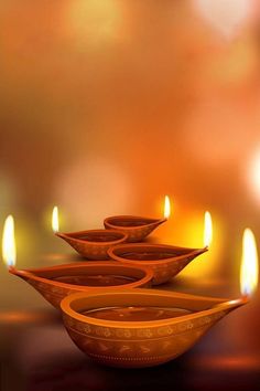 three orange bowls with lit candles in the background