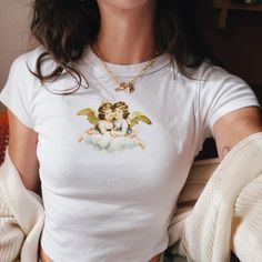 We love this fun, colorful cute Vintage Angels Baby Tee! This adult sized tee is soft and super comfy and is made of 52% cotton and 48% polyester for a luxurious lightweight stretch. The designs are printed with DTF which delivers a vivid, detailed design with a textured feel. This tee is a perfect blend of coquette fashion and nostalgic Y2K vibes, making it a trendy addition to your casual wardrobe. Made with soft, comfortable material, it's ideal for everyday wear or for making a statement at White Cotton Aesthetic T-shirt, Cute Fitted Tops With Cartoon Print, Aesthetic Crew Neck Top With Graphic Print, Aesthetic Graphic Print Crew Neck Top, Aesthetic Cotton Top With Graphic Print, Aesthetic Graphic Print Tops For Spring, White Aesthetic T-shirt With Letter Print, Aesthetic Cotton Crew Neck Tops, Aesthetic White Tops With Graphic Print