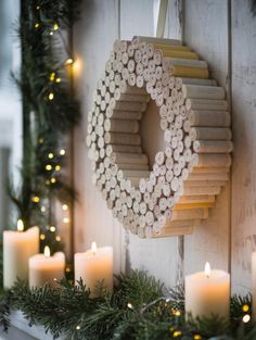 a wreath made out of wine corks is hung on the wall next to candles