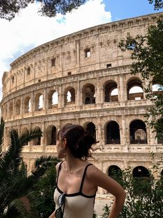 a woman standing in front of the colossion looking at the sky with her hands on her hips