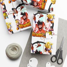 the wrapping paper is decorated with dragon ball and cartoon character images, scissors, twine string, and yarn