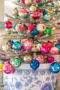 a christmas tree with ornaments in a blue and white potted planter on a table