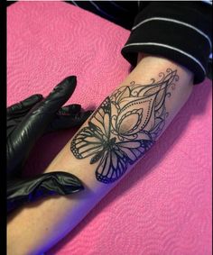 a woman's arm with a butterfly tattoo on it and gloves next to her