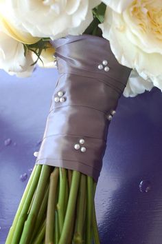 the bridal bouquet is wrapped in satin material and has pearls on it, along with white roses